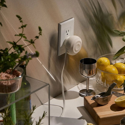 White ceramic plug-in diffuser with a smooth, rounded design and a subtle spiral pattern on its surface.
