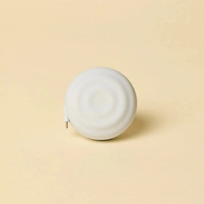 White, circular tape measure with a smooth, matte finish and a metallic tip.