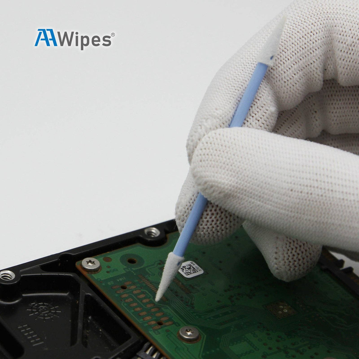A close-up of a gloved hand using a blue and white cleaning swab to clean a green circuit board on a hard drive, with the AAWipes logo in the top left corner.