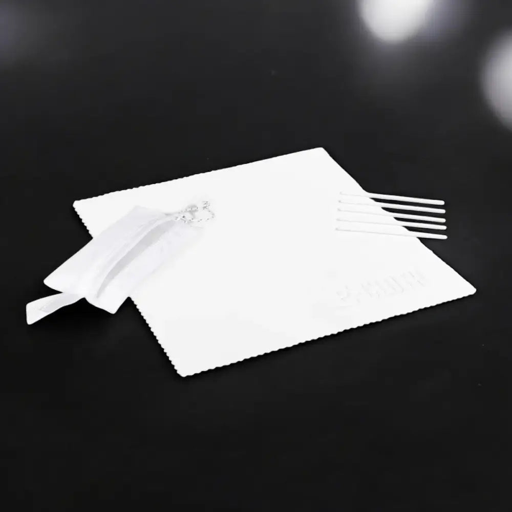 White microfiber cleaning cloth with a small silver decorative charm and five white plastic applicator sticks.