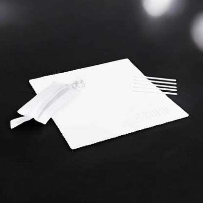 White microfiber cleaning cloth with a small silver decorative charm and five white plastic applicator sticks.