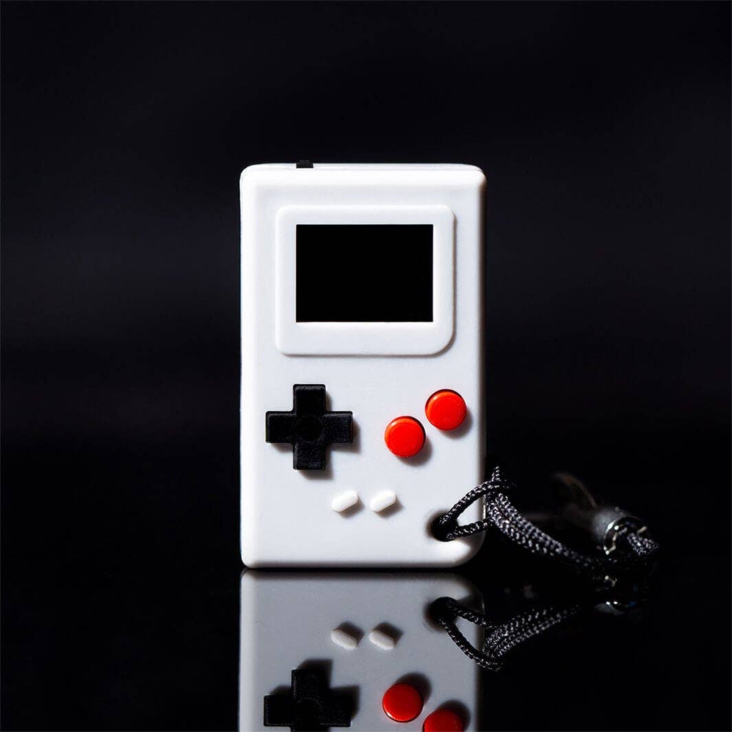 White handheld gaming console with red and black buttons on a reflective surface with a dark background