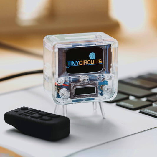 Transparent electronic device with 'TINYCIRCUITS' branding on a desk.