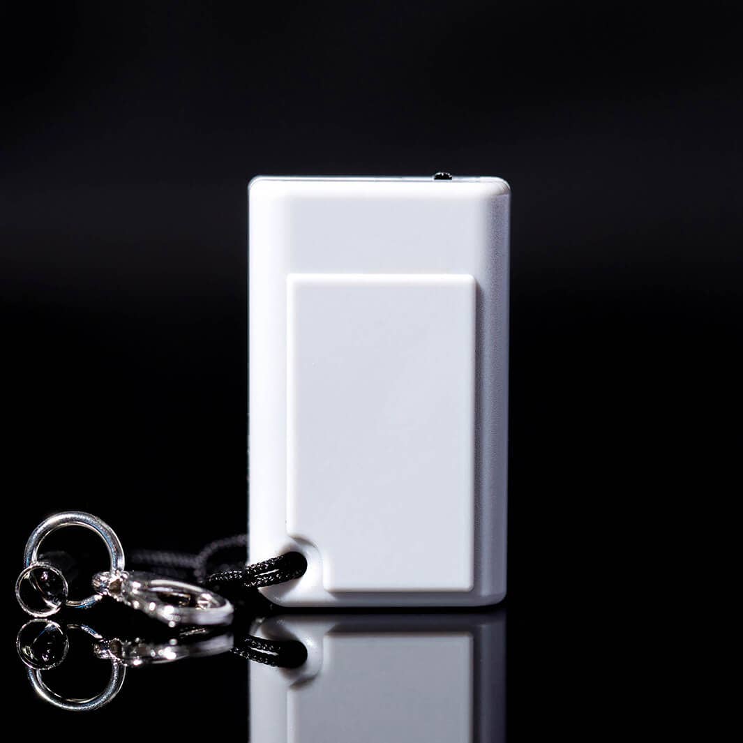 The back of the gray tiny game console on a black background with a keychain attached. 