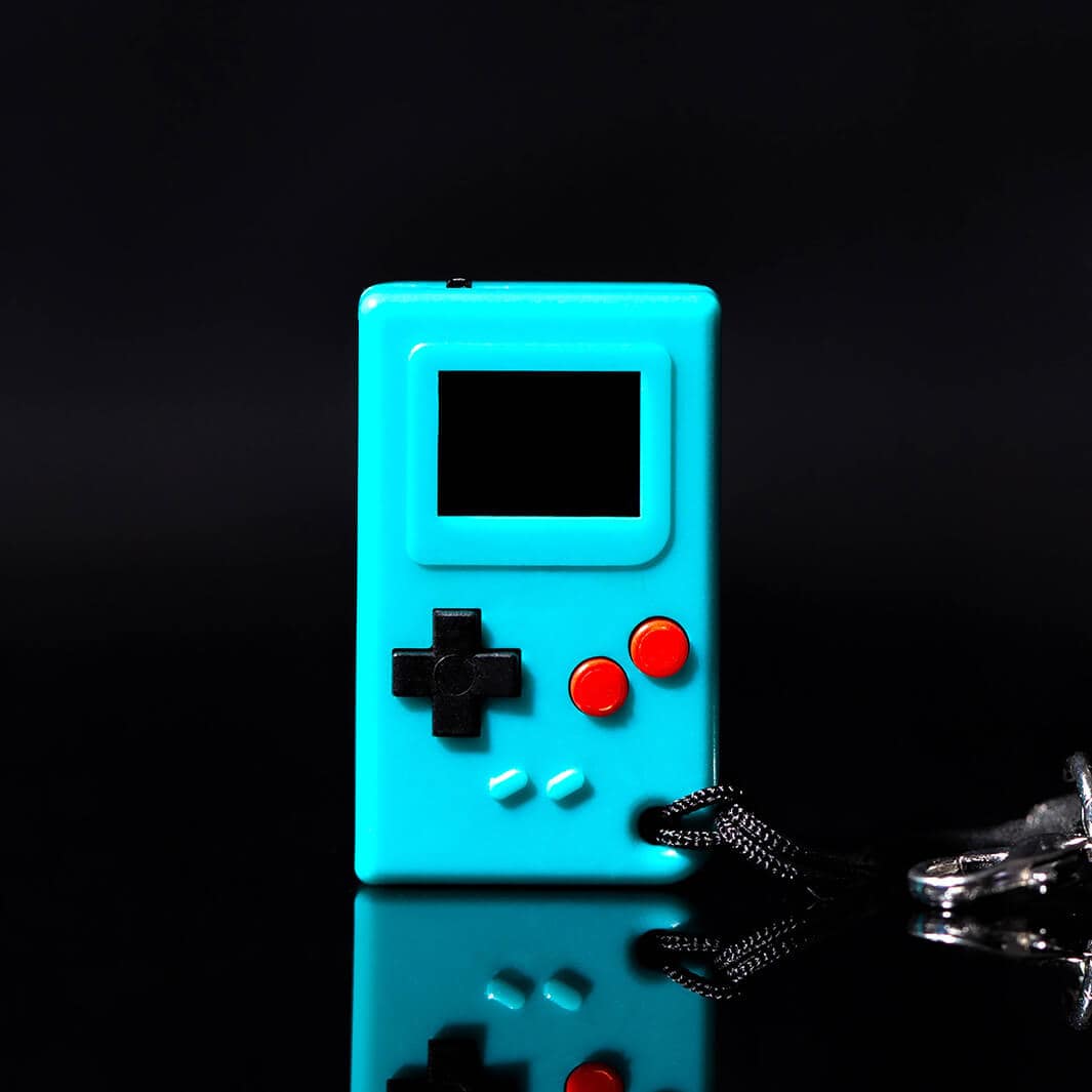 Teal handheld game console with black and red buttons on a reflective surface.