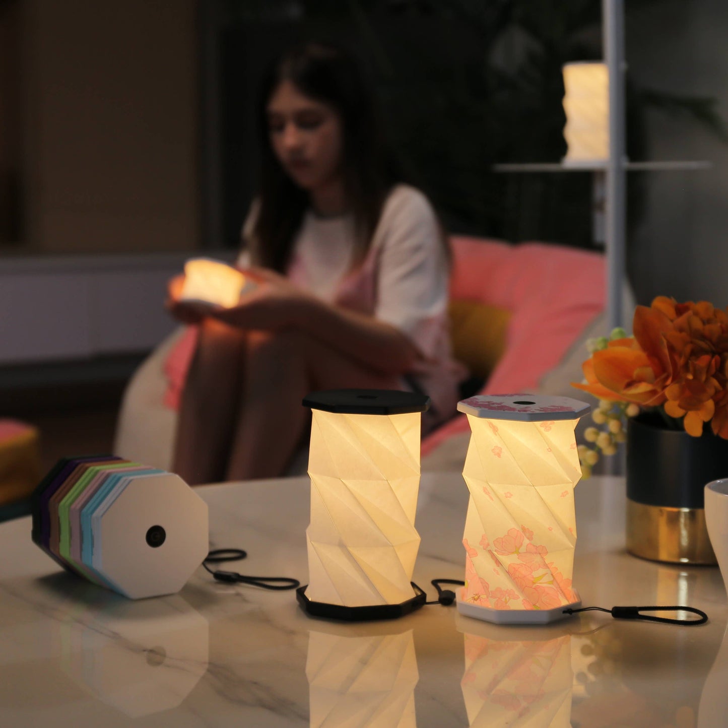 Two illuminated lanterns on a table with a person sitting in the background.