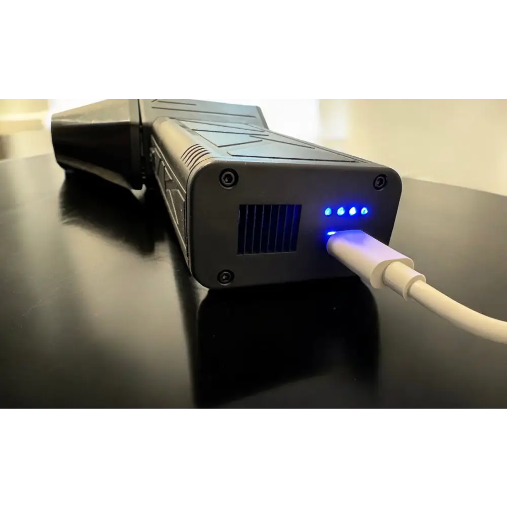 Black rugged power bank with blue led indicators and a white usb cable plugged in.