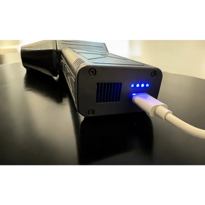 Black rugged power bank with blue led indicators and a white usb cable plugged in.