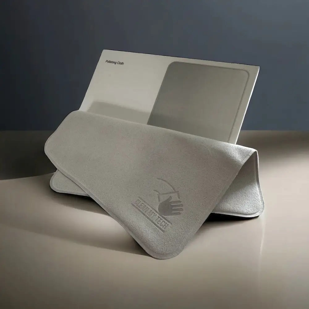 A soft, light gray microfiber polishing cloth with a subtle embossed logo and text.