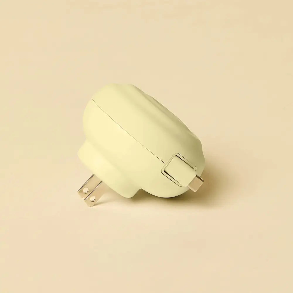 Cream-colored, rounded plug-in charger with a sleek matte finish and metallic prongs.