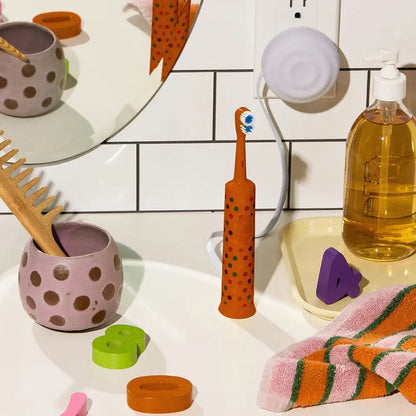 Orange polka-dotted electric toothbrush with blue and white bristles