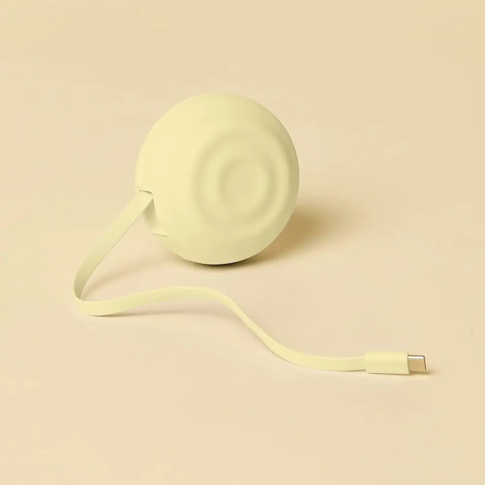A soft, pale green circular portable charger with a smooth matte finish and concentric ridges on its surface.