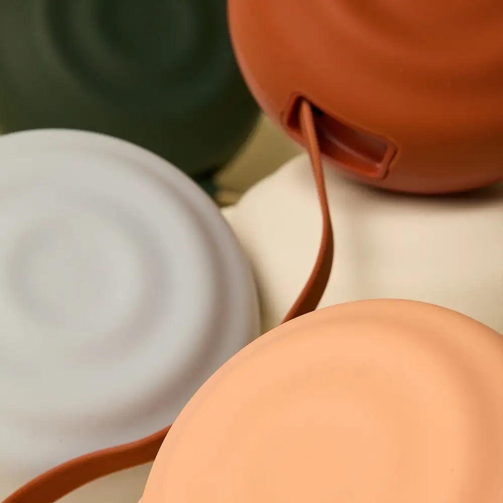 Terracotta-colored silicone travel mug with a matching strap.