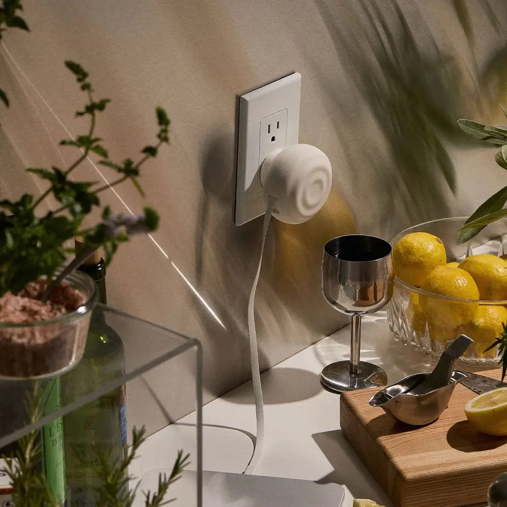 White ceramic plug-in diffuser with a smooth, rounded design and a subtle spiral pattern on its surface.