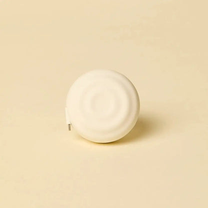 White ceramic tape measure with a smooth, rounded design and subtle concentric ridges.