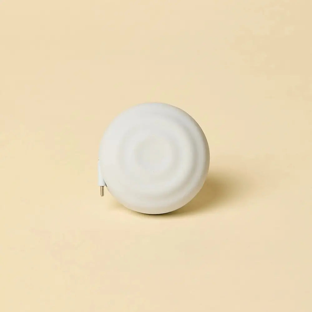 White, circular tape measure with a smooth, matte finish and a metallic tip.