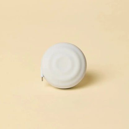 White, circular tape measure with a smooth, matte finish and a metallic tip.