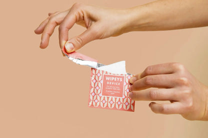 A pink and white geometric-patterned package containing a single-use wipe, labeled ’wipey’s device’ for all-day clean.